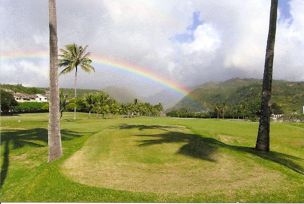 A rainbow crosses over a golf fairway