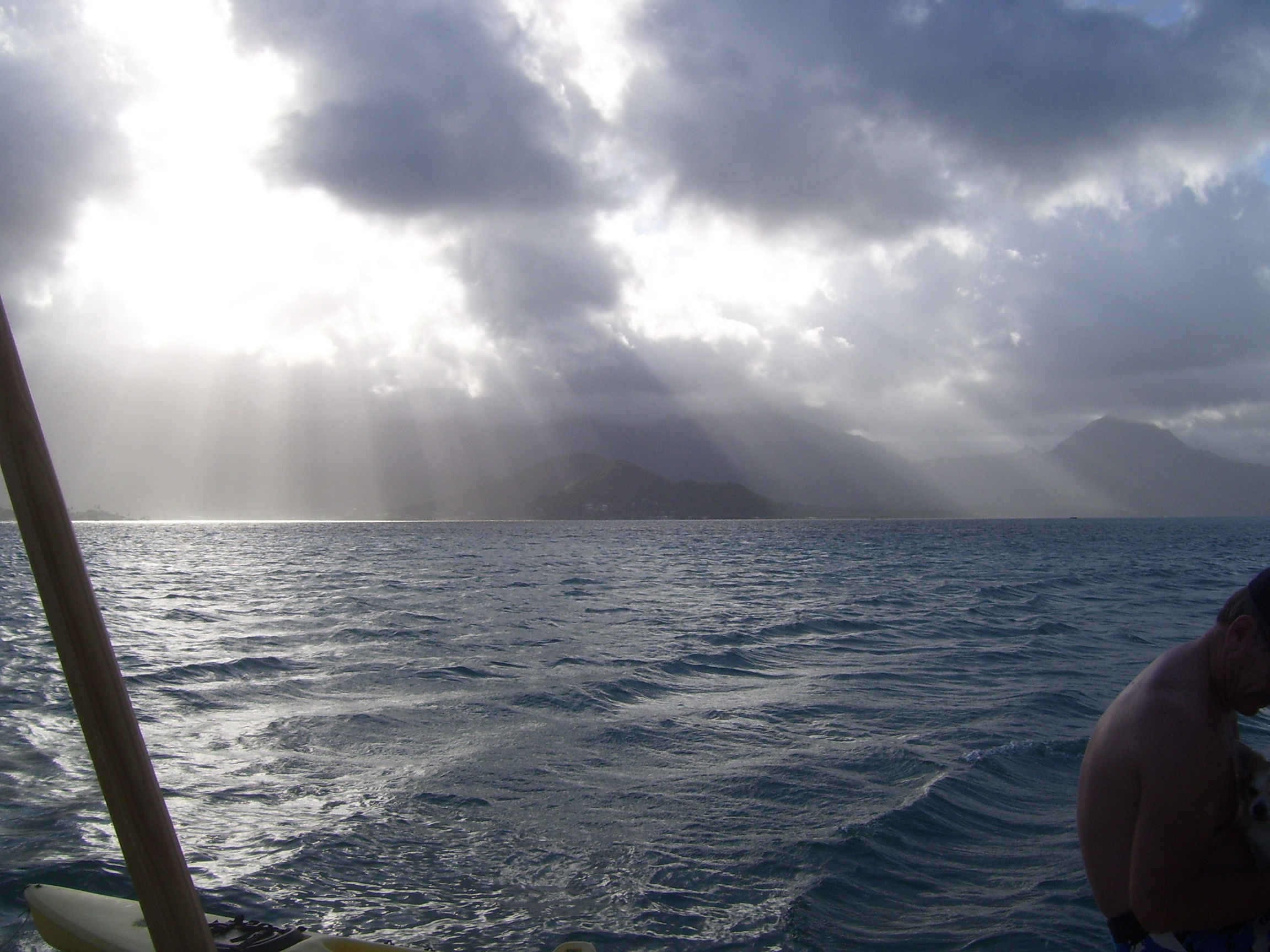 Light rays stream through holes in the dark clouds at Kaneohe Bay