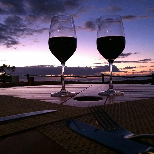 Two glasses of red wine with Hawaiian sunset in background