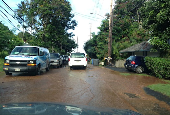 Brown water crosses the road as cars sit on Kamehameha highway