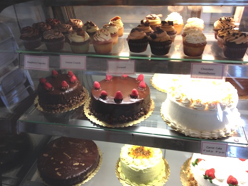 A storefront display of various cakes and pies at Cake Works