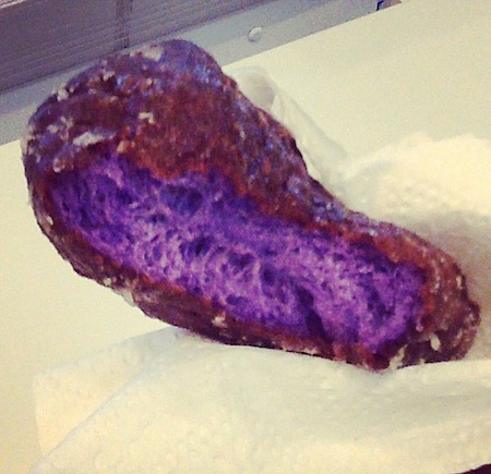 Half-eaten purple poi donut from Kamehameha Bakery