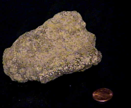 A close up of a lava rock next to a penny