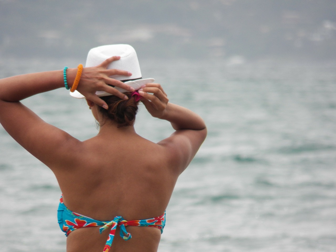 Oman on the beach holding onto a hat