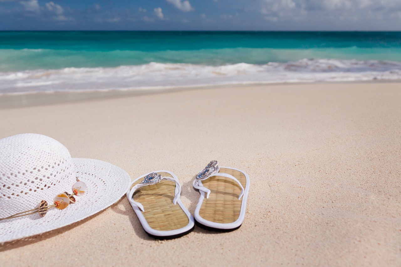 A hat and slippahs sitting on a beach