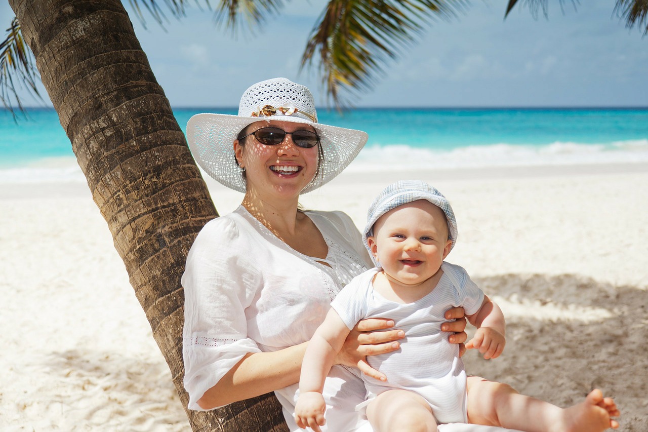 A baby sites on Mother's lap on the beach