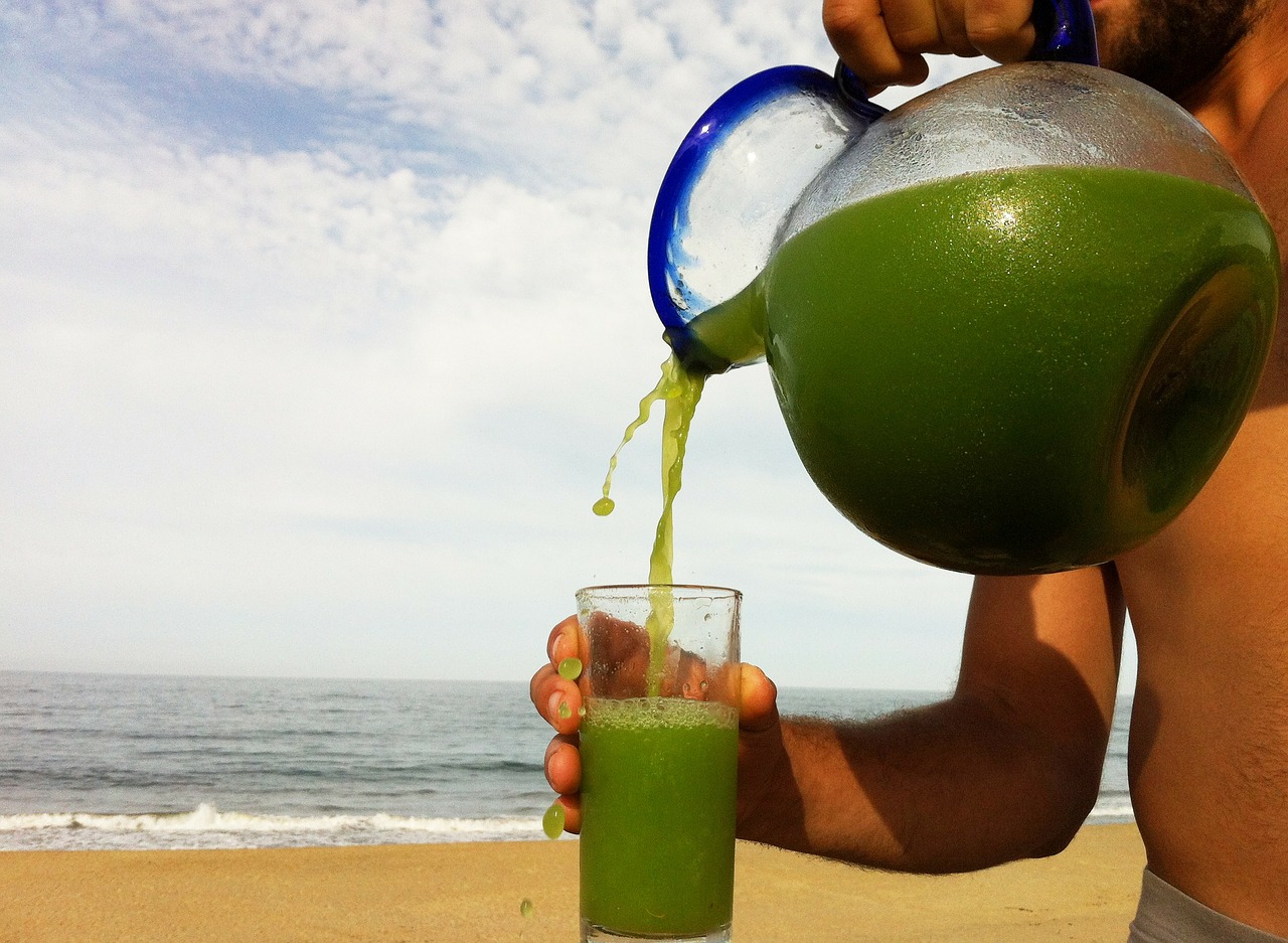 A man pours organic juice on the beach