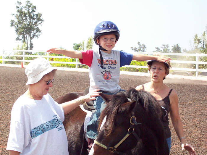A young girl stretches her arms while sitting on a Horse