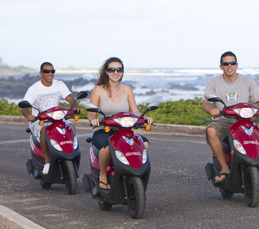 Three people driving mopeds