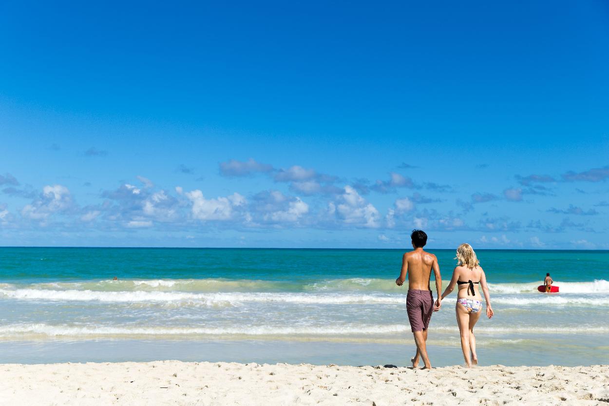 couple holding hands while walking on the beach