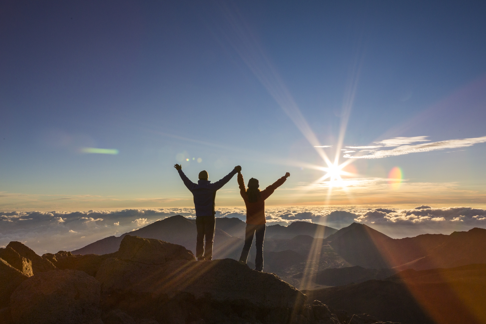 people on haleakala holding outstreached arms and holding hands