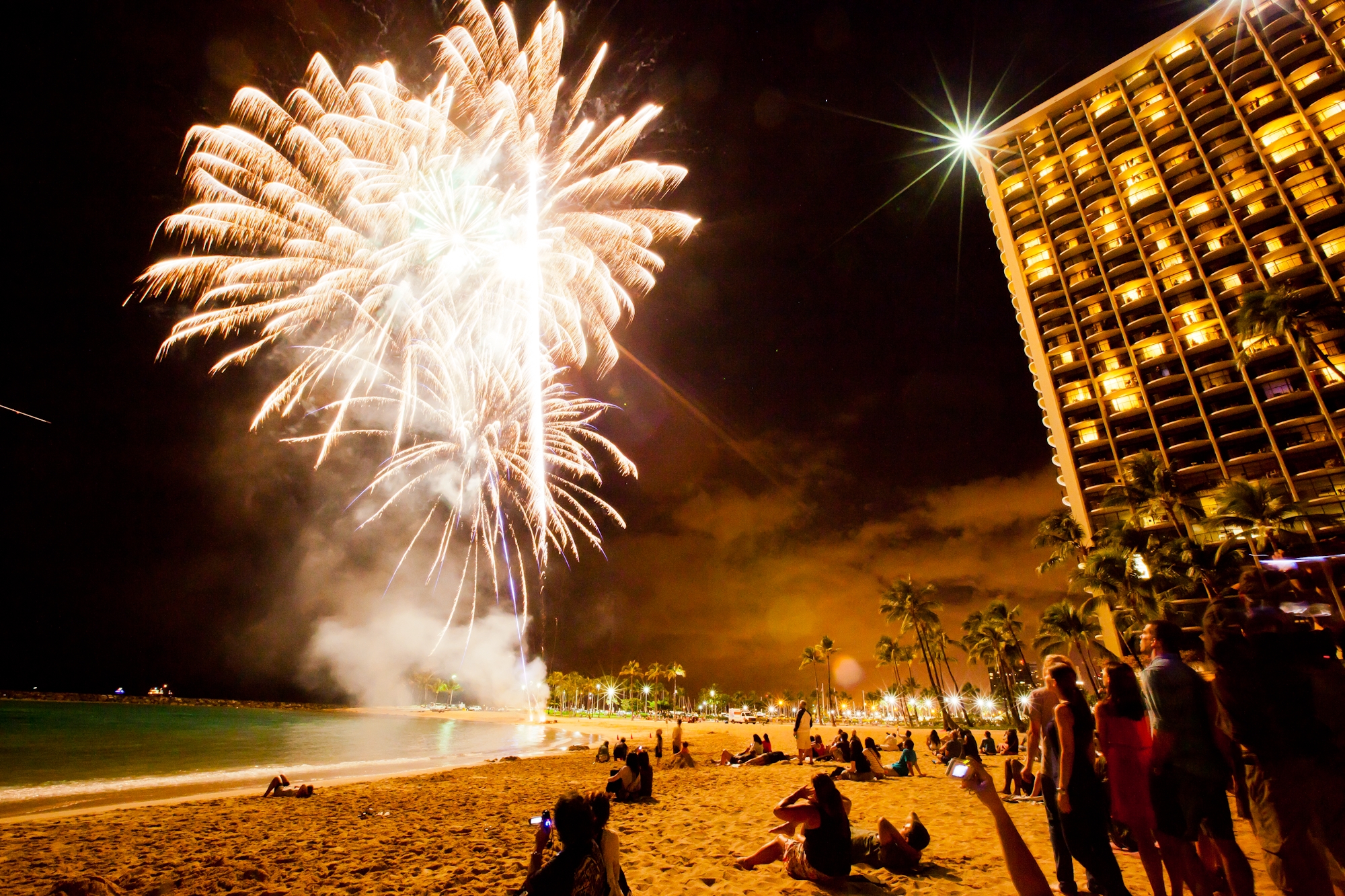 people on a beach watching fireworks