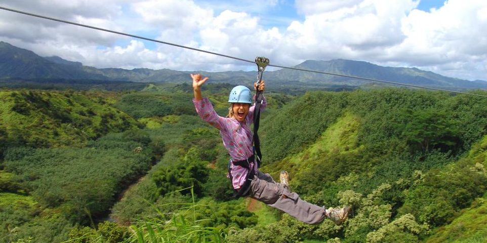 a woman zip lining through a rainforest