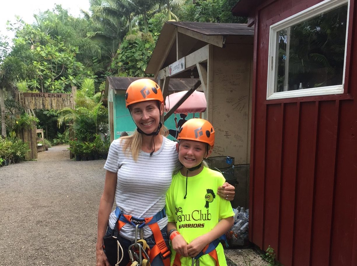 a woman and girl with ziplining equipment on