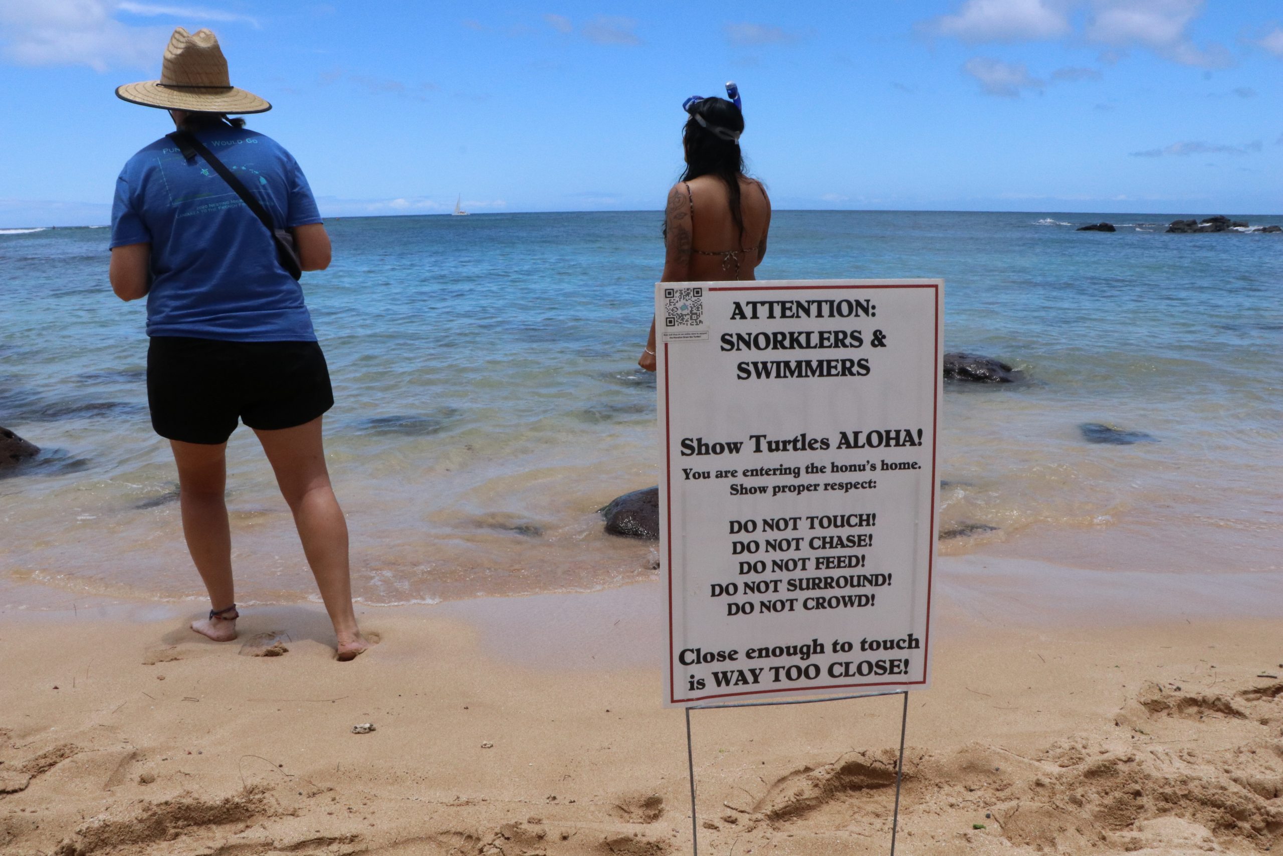 Warning signs at Oahu beach with swimmers standing in front of them
