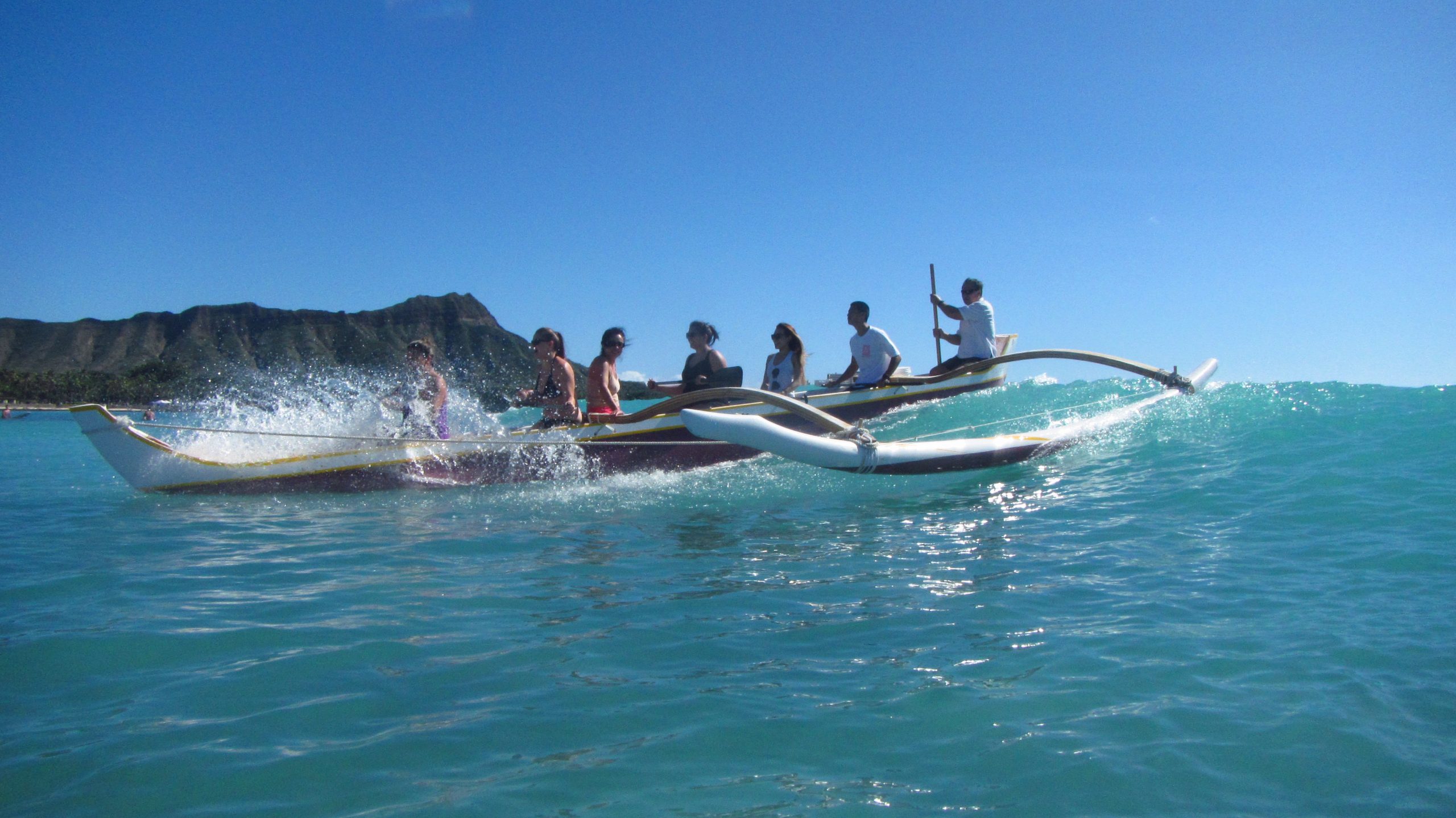 People in a Outrigger canoe padding with Waikiki Beach Services