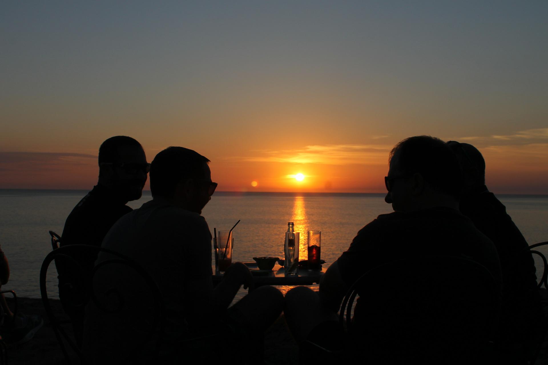 People in silhouette dining at sunset at Hawaii sports bar