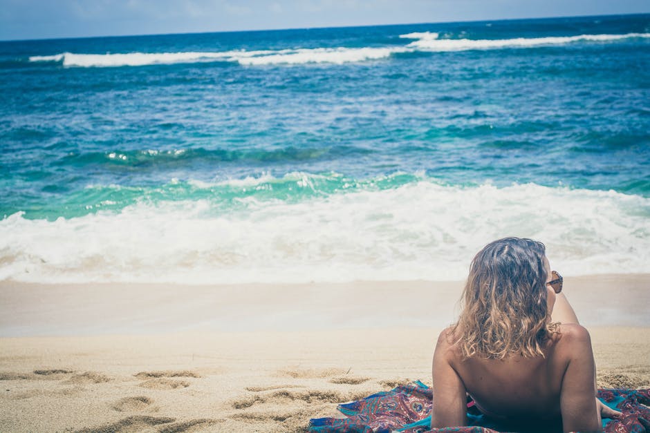 Woman laying on towel looking toward the beach 