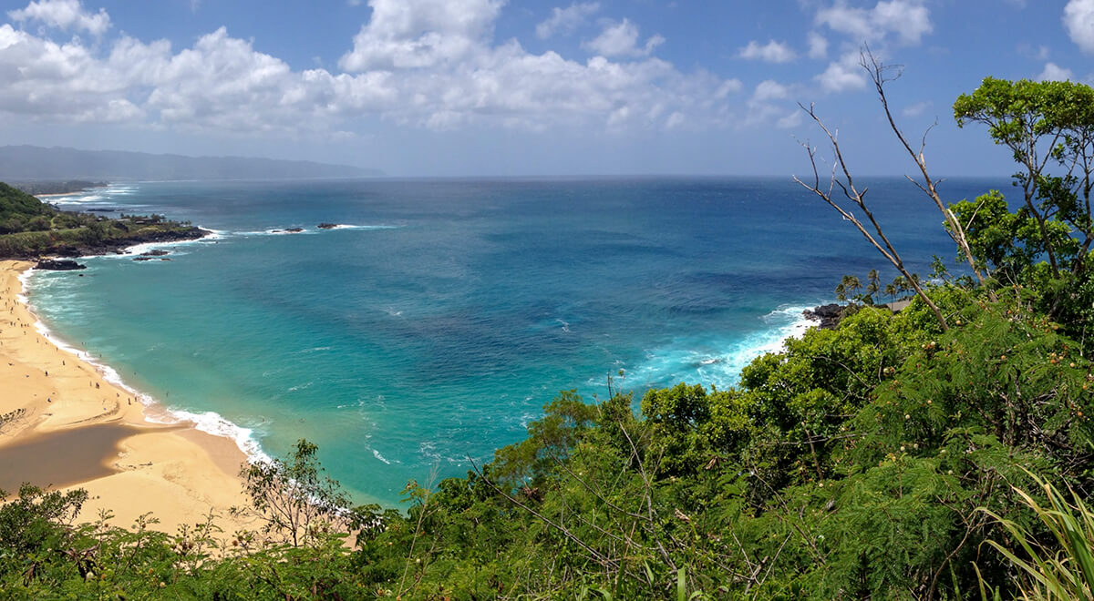 Aerial shot overlooking Waimea bay showing sand and ocean 