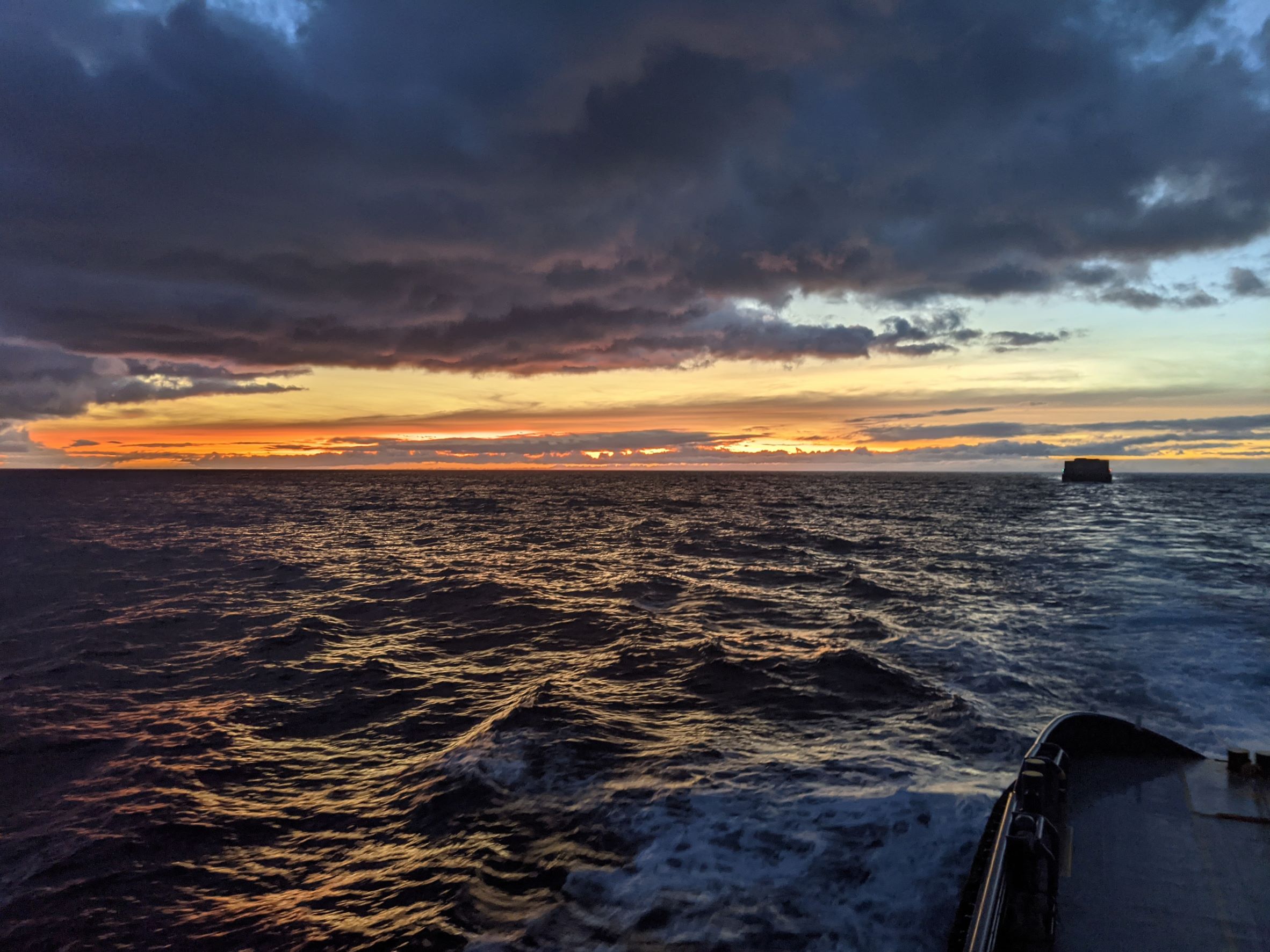 View of Hawaii sunrise from tugboat with barge.