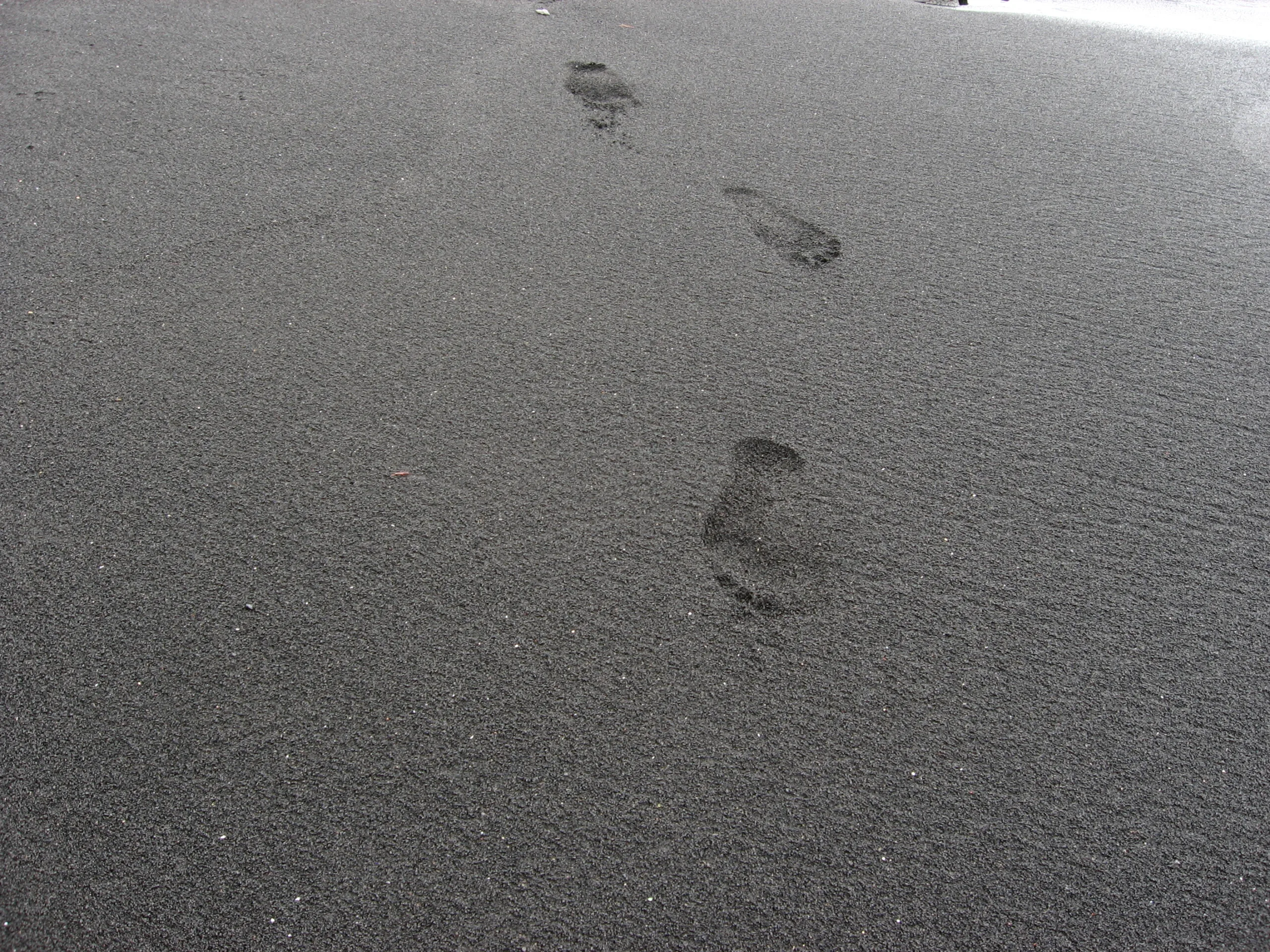 footprints on black sand beach