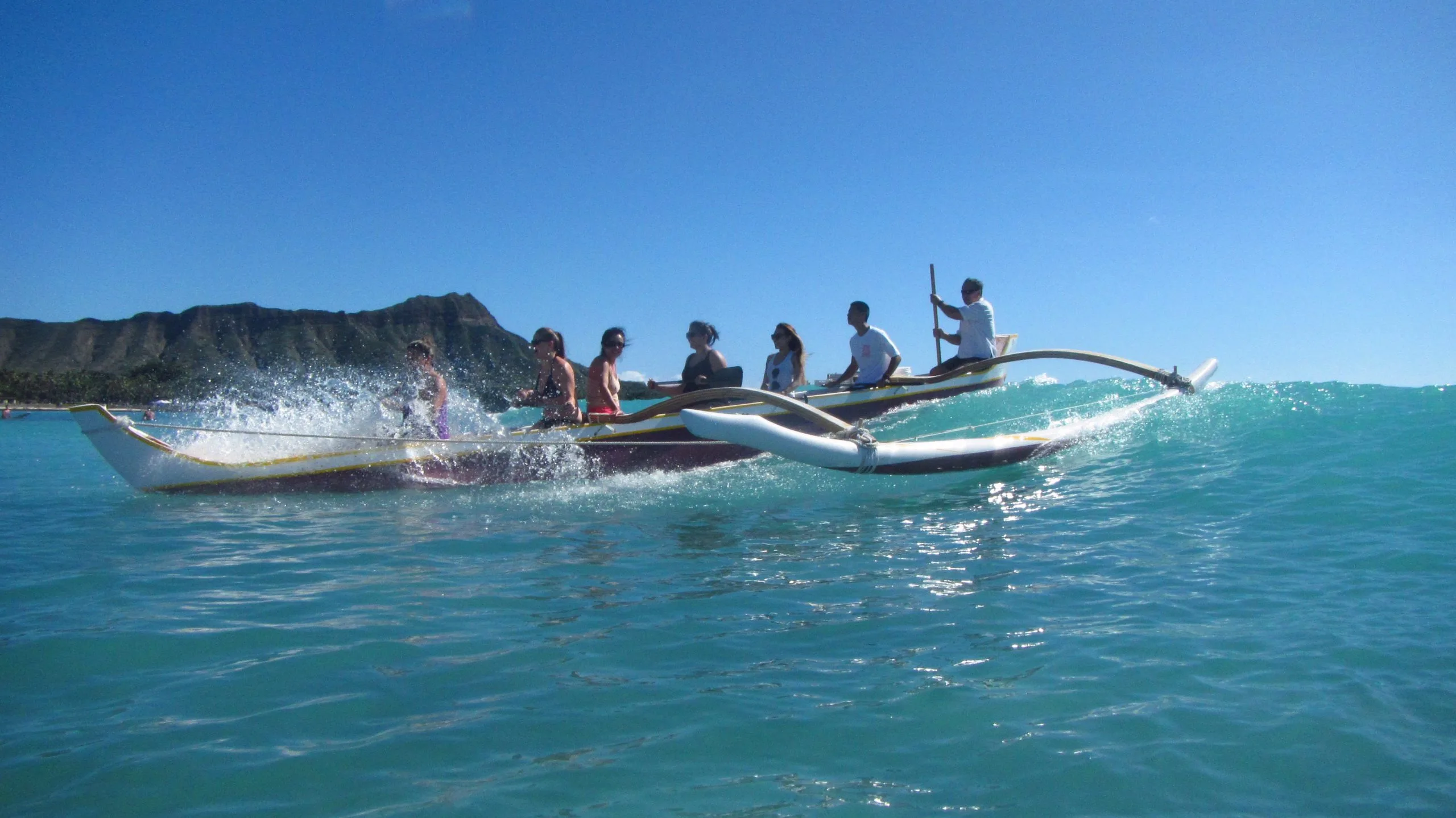 People in a Outrigger canoe padding with Waikiki Beach Services